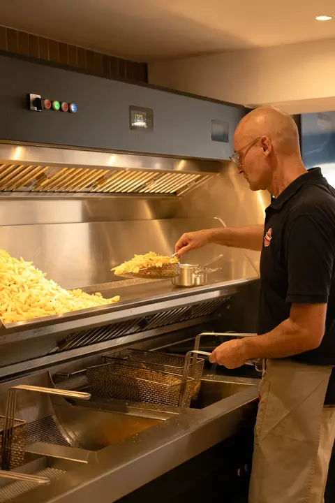 Olivier prépare les frites devant l’installation de friterie de Quai 18